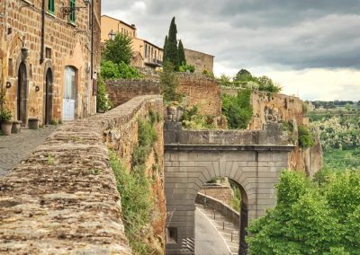 A monumental medieval stone gate guarding the entrance to an Italian hill town.