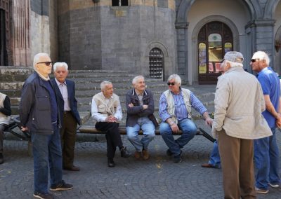 A group of local Italian men conversing during a traditional afternoon passeggiata walk.