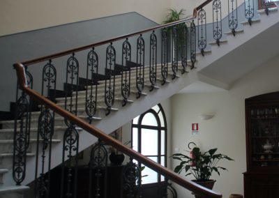 A sweeping marble grand staircase with ornate wrought-iron railings in a historic hotel.