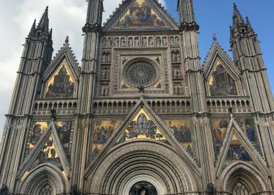 The intricate green, pink, and white marble front facade of the Florence Duomo.