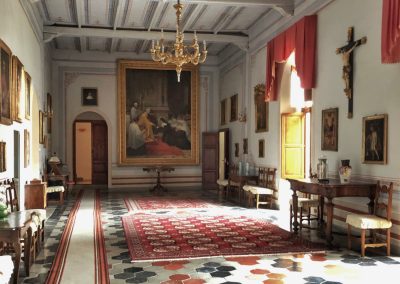 A spacious historic great room with timber ceiling beams and a large stone fireplace.