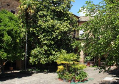 A historic stone accommodation courtyard viewed through lush garden flowers.