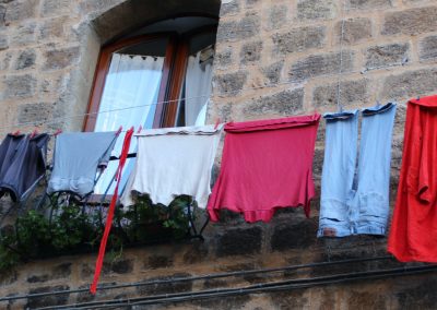 Fresh laundry hanging on clotheslines high across a narrow Italian alleyway.