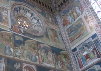 A historic painted monument and fresco on the interior stone wall of the Duomo.
