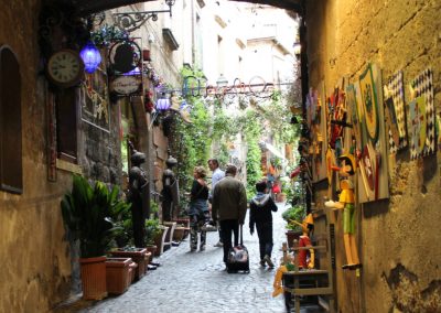A rustic boutique storefront with handmade crafts displayed on a cobblestone street.