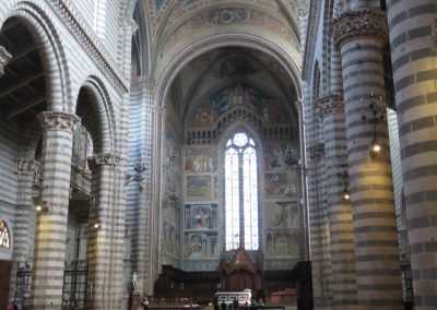 A sweeping wide-angle view down the central nave of a grand Italian Duomo.