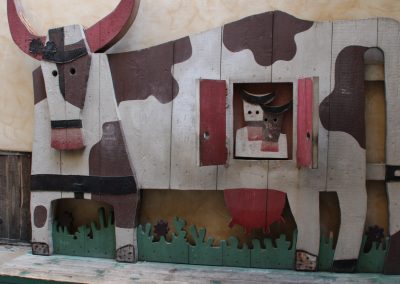 A rustic public cow sculpture made from corrugated industrial metal.
